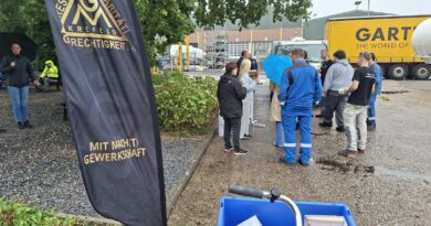 Beachflag der IG Metall Krefeld im Vordergrund, dahinter Kolleginnen und Kollegen von GOFA mit Eis im Innenhof