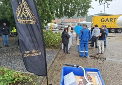 Beachflag der IG Metall Krefeld im Vordergrund, dahinter Kolleginnen und Kollegen von GOFA mit Eis im Innenhof