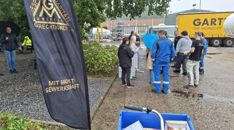 Beachflag der IG Metall Krefeld im Vordergrund, dahinter Kolleginnen und Kollegen von GOFA mit Eis im Innenhof